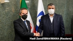 Ketua Badan Pengawas Nuklir PBB (IAEA) Rafael Grossi (kiri) berjabat tangan dengan Kepala Organisasi Energi Atom Iran Mohammad Eslami dalam pertemuan di Teheran pada 23 November 2021. (Foto: ISNA/WANA/via Reuters/Hadi Zand)