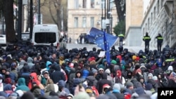 Manifestantes antigovernamentais concentram-se em frente ao edifício do parlamento enquanto os deputados elegem um novo presidente em Tbilissi, a 14 de dezembro de 2024.