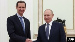 In this pool photograph distributed by the Russian state agency Sputnik on July 25, 2024, Russia's President Vladimir Putin, right, shakes hands with Syria's President Bashar al-Assad during their meeting at the Kremlin in Moscow on July 24, 2024.