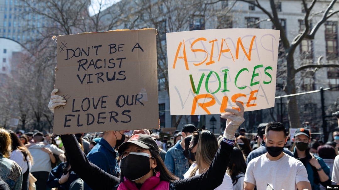 Seorang perempuan menunjukkan poster dalan pawai menentang kejahatan rasial terhadap orang Amerika keturunan Asia dan Kepulauan Pasifik di Kota New York, 21 Maret 2021. 