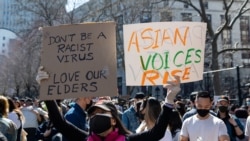 FILE - A woman holds up signs during a Rally Against Hate to end discrimination against Asian Americans and Pacific Islanders in New York City, March 21, 2021.