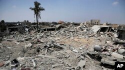 Palestinians search the rubble to collect what they can from their family destroyed houses, hit by Israeli strikes in Khuzaa, east of Khan Younis, northern Gaza Strip, Aug. 5, 2014. 