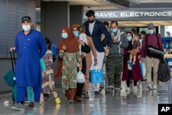 FILE - In this Aug. 31, 2021, file photo, families evacuated from Kabul, walk through the terminal to board a bus after they arrived in Washington.