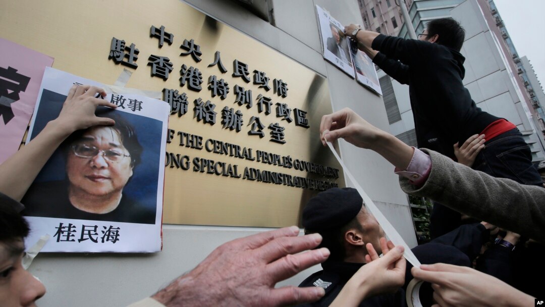 香港抗議者在北京駐香港機構中聯辦前貼上銅鑼灣書店失踪老闆桂民海的照片。 （2016年1月3日）