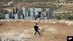 Palestinians throw stones at Israeli settlers who are later detained by Palestinian villagers in a building under construction near the West Bank village of Qusra, southeast of the city of Nablus, Jan. 7, 2014.