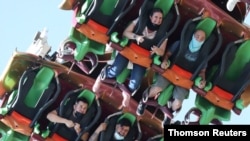 People ride a roller coaster at Six Flags Magic Mountain amusement park on the first day of opening, as the coronavirus disease (COVID-19) continues, in Valencia, California, April 1, 2021. 