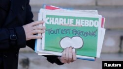 El primer ministro francés, Manuel Valls, sostiene una copia de Charlie Hebdo al salir del Palacio de los Eliseos, en París.