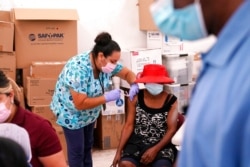 A nurse administers the Johnson & Johnson COVID-19 vaccine to Rosemene Lordeus, right, at a clinic held by Healthcare Network in Immokalee, Fla., April 10, 2021.