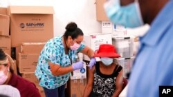 FILE - A nurse administers the Johnson & Johnson COVID-19 vaccine to Rosemene Lordeus, right, at a clinic held by Healthcare Network in Immokalee, Fla., April 10, 2021.