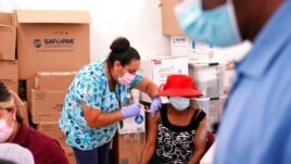 A nurse administers the Johnson & Johnson COVID-19 vaccine to Rosemene Lordeus, right, at a clinic held by Healthcare Network in Immokalee, Fla., April 10, 2021.