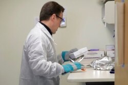 FILE - A pharmacist in Seattle opens a package taken from a freezer that contains a potential vaccine for COVID-19, on the first day of a first-stage safety study clinical trial of the vaccine, March 16, 2020.