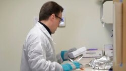 A pharmacist in Seattle opens a package taken from a freezer that contains a potential vaccine for COVID-19, on the first day of a first-stage safety study clinical trial of the vaccine, March 16, 2020.