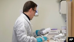 A pharmacist in Seattle opens a package taken from a freezer that contains a potential vaccine for COVID-19, on the first day of a first-stage safety study clinical trial of the vaccine, March 16, 2020.