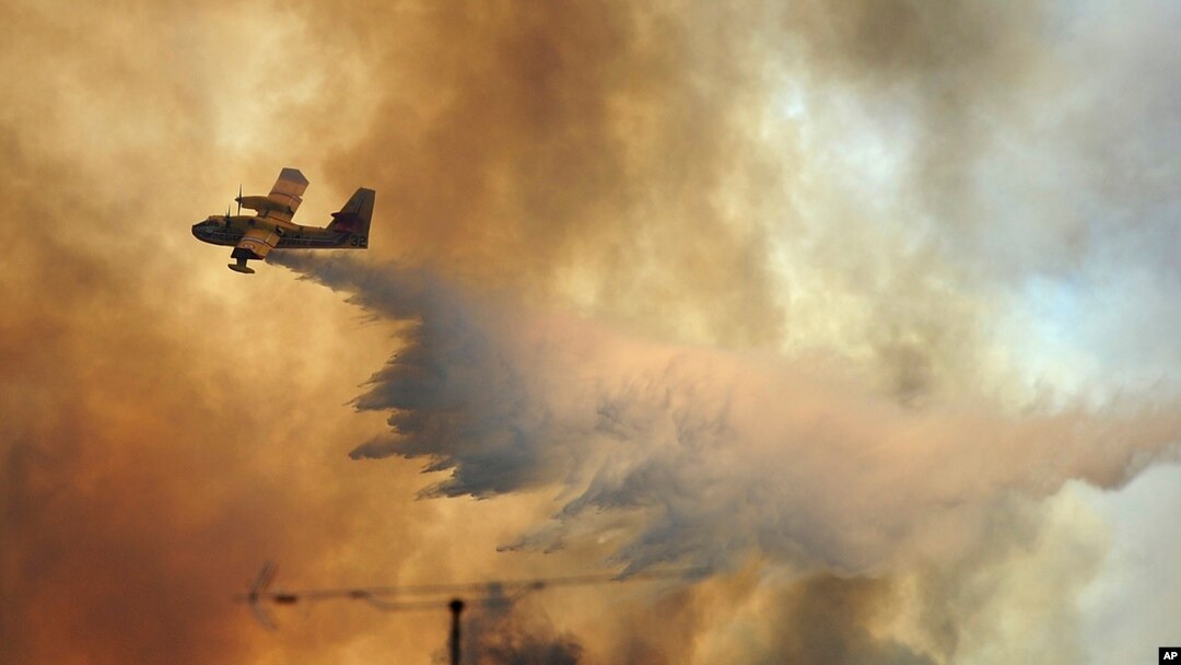 Sebuah pesawat pemadam kebakaran menyiramkan air di atas kobaran api kebakaran hutan di luar desa Pedrogao Grande, Portugis tengah (19/6).