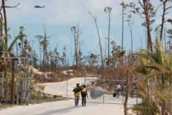 People walk to a private airport in the aftermath of Hurricane Dorian, looking to be evacuated, in Marsh Harbor, Abaco Island, Bahamas, Sept. 6, 2019.