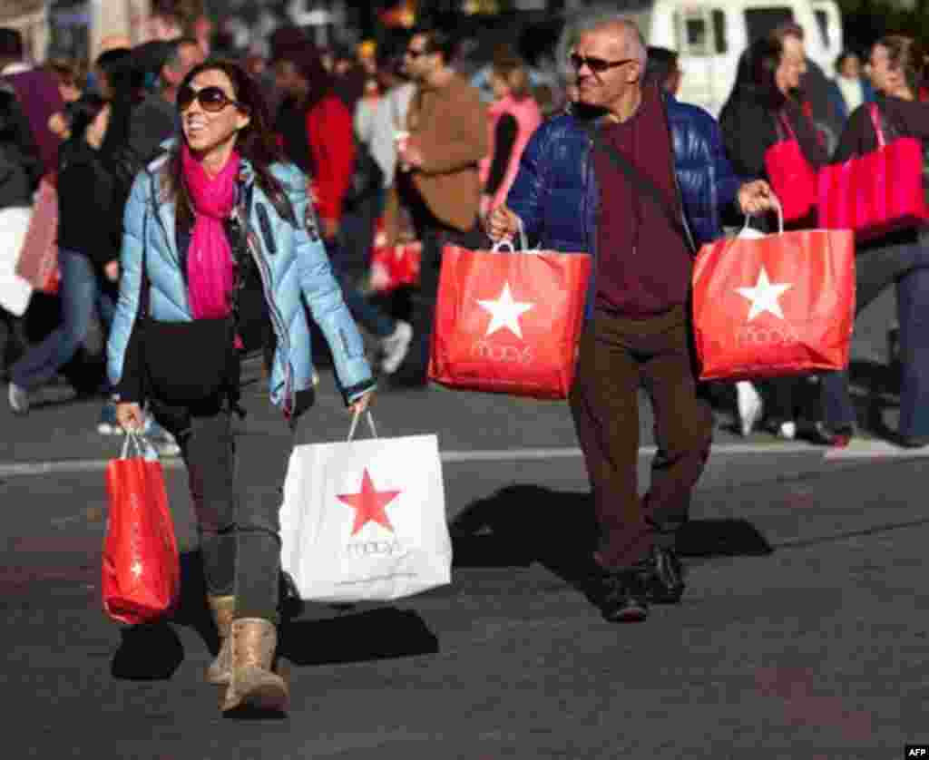 FILE - In this Nov. 25, 2011 file photo, consumers lug their bags through Herald Square during the busiest shopping day of the year, in New York. A private research group says consumer�s confidence in the economy in November soared 15 points to its highes