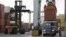 Driver watches as a freight container is lowered onto a tractor trailer by crane, Port of Boston, Dec. 18, 2012.
