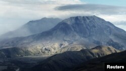 FILE - Dirt and ash continues to drift out from inside the crater of Mount St. Helens after a small eruption earlier in the day, Oct. 5, 2004.