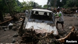 A man removes debris from his vehicle along a road in Arayat, Pampanga, that was hit by Typhoon Nari in the northern Philippines, October 13, 2013.