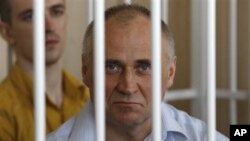A former opposition presidential candidate Mikola Statkevich sits in a cage during a court session in Minsk, Belarus, Thursday, May 26, 2011.
