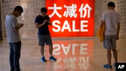资料照片: 2016年7月10日中国北京购物区促销广告和购物者
