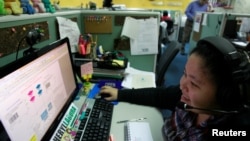 FILE - A call center agent talks to a client in the U.S. as she works the overnight shift in Manila's Makati financial district, Feb. 6, 2012. 