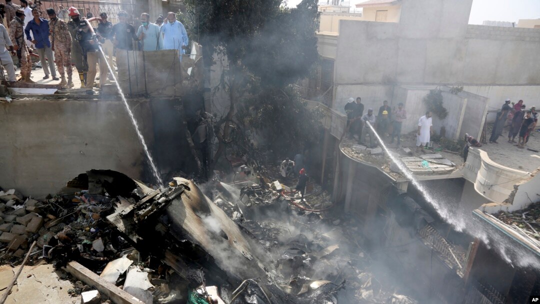 Fire brigade staff try to put out fire caused by plane crash in Karachi, Pakistan, May 22, 2020.