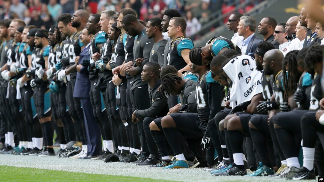 Jacksonville Jaguars players lock arms and kneel down during the playing of the U.S. national anthem before an NFL football game against the Baltimore Ravens at Wembley Stadium in London, Britain, Sept. 24, 2017. 