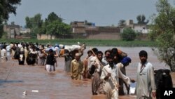 Evacuating residents carry their belongings through floodwaters the Mohib Bhanda area in Nowshera district, Pakistan, 31 Jul 2010