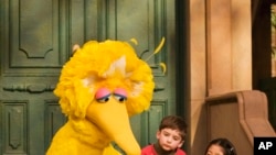 FILE - Big Bird, voiced by Caroll Spinney, reads to children during a taping of Sesame Street in New York, April 10, 2008. 