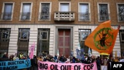 FILE - Environmental activists hold up placards during a demonstration outside the headquarters of BP in central London on December 9, 2023, gathering in solidarity with people on the frontlines of the climate crisis. 