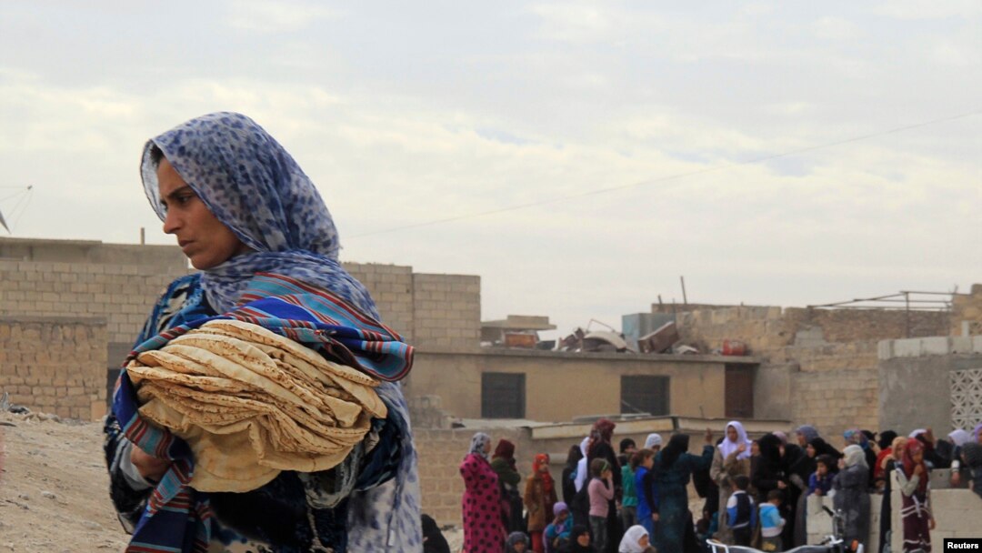 Seorang perempuan memegang roti di kota Minbij di sebelah timur Aleppo, Suriah. (Foto: Dok)