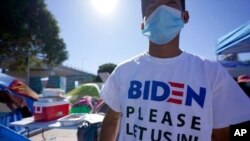 un hombre de Honduras en busca de asilo en los Estados Unidos lleva una camisa que dice: "Biden favor déjanos entrar", el 1 de marzo, en Tijuana, México.