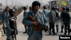 FILE - Afghan policemen keep watch at the site of clashes with protesters in Kabul, Jan. 31, 2015. 