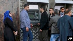 Employees wait in line in at a cash machine to receive their monthly salaries in Gaza City, April 5, 2017. The cash-strapped Palestinian Authority said it has slashed the salaries of some 50,000 government employees in the Gaza Strip.