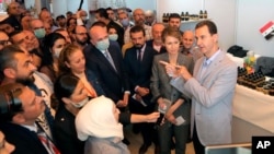 Syrian President Bashar Assad, right, and first lady Asma Assad, center right, speaks with people during his visit to the Producers exhibition, in Damascus, Syria, Nov. 4, 2020.