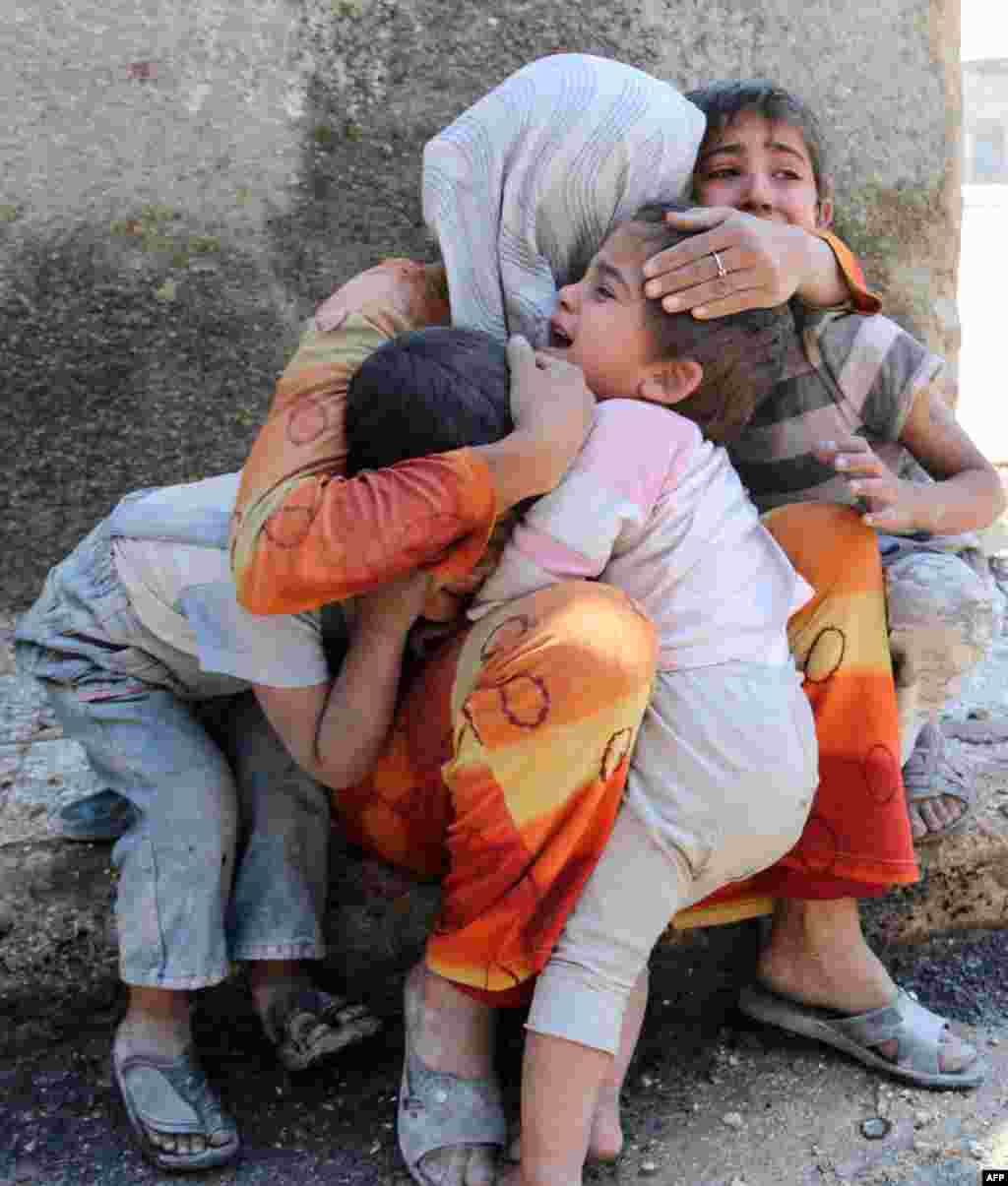 A Syrian woman comforts her children after their house in the Sahour nieghborhood of the northern Syrian city of Aleppo was bombed.