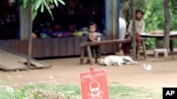 Children sit near a minefield outside their home in the northwestern Cambodian province of Battambang, one of the most heavily-mined in the country