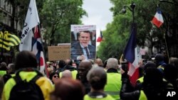 Yellow vest protesters, one carrying a placard with a picture and a quote of French President Emmanuel Macron ("Let them come get me"), march in Paris, May 4, 2019.