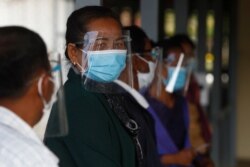 Civic group members wait in queue before getting into the court room of the U.N.-backed war crimes tribunal in Phnom Penh, Cambodia, Aug. 16, 2021.