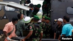 Para prajurit mengeluarkan jenasah prajurit korban serangan kelompok sipil bersenjata, setibanya di bandara Sentani, Papua (22/2/2013)