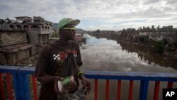 Venel Ceus 29, a street vendor stands against the bridge of a canal in Cap Haitien, Haiti, April 1, 2015. Many Haitians are not eager to see the development of mining, skeptical of an industry that could pollute a country with a history of weak regulation and environmental problems.