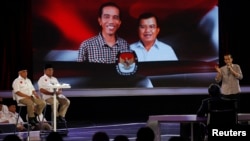 Kandidat presiden Indonesia Joko "Jokowi" Widodo (kanan) dalam debat yang disiarkan langsung di televisi dengan saingannya Prabowo Subianto dan Hatta Rajasa (kiri) di Jakarta, 5 Juli 2014. 