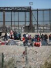 Migrants line up at the U.S. border wall after being detained by U.S. immigration authorities, seen from Ciudad Juarez, Mexico, Dec. 27, 2023. 