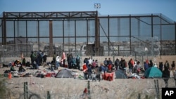 Migrantes hacen fila en el muro fronterizo de Estados Unidos después de ser detenidos por las autoridades de inmigración estadounidenses, visto desde Ciudad Juárez, México, el 27 de diciembre de 2023. ​