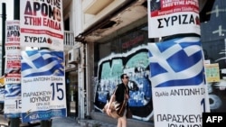 A man passes by election posters of the conservative new Democracy party and the left coalition Syriza party in central Athens, June 13, 2012.