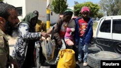 Members of Libyan internationally-recognized government forces evacuate an African family during the fighting with Eastern forces, at Al-Swani area in Tripoli, Libya, April 18, 2019. 