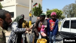 FILE - Members of Libyan internationally-recognized government forces evacuate an African family during the fighting with Eastern forces, at Al-Swani area in Tripoli, Libya, April 18, 2019. 