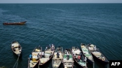 FILE - Fishermen prepare their nets aboard their boats on Migingo island, which is densely populated by residents fishing mainly for Nile perch in Lake Victoria on the border of Uganda and Kenya, on Oct. 5, 2018. 