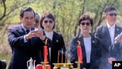 FILE - In this photo released by Xinhua News Agency, former Taiwan President Ma Ying-jeou, left, makes a libation as he paying respect to his grandfather's tomb in Xiangtan county, in central China's Hunan province, April 1, 2023. 